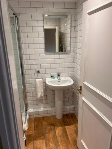 a white bathroom with a sink and a mirror at Ganton Greyhound Hotel in Ganton