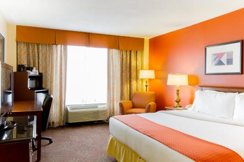 a hotel room with a bed and a chair and a window at Holiday Inn O'Hare Area by IHG in Rosemont