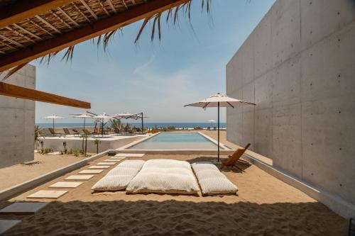 a row of lounge chairs and an umbrella next to a swimming pool at Casa Talá by Lumina in Puerto Escondido