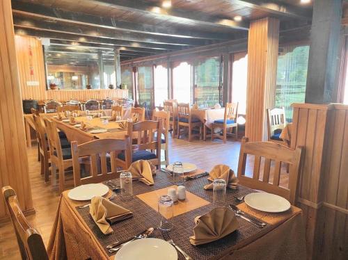 a dining room with wooden tables and chairs and tablesearcher at Tshang Tshang Villa in Paro