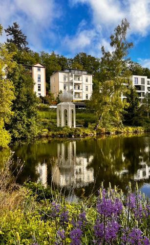 a garden with a pond in front of a building at Penthouse am Kurparkweiher in Bad Schwalbach