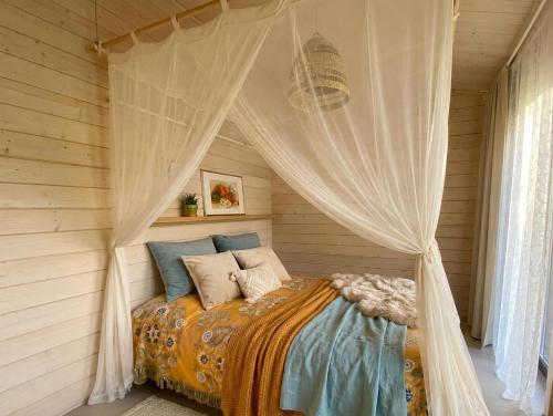 a bed with a canopy in a room at Ezermāja "Spārītes" in Geraņimova