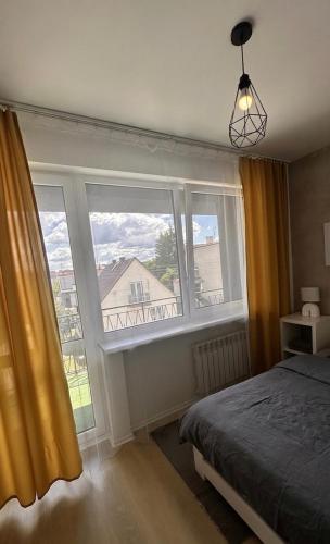 a bedroom with a bed and two large windows at Apartamenty W Domu in Białystok
