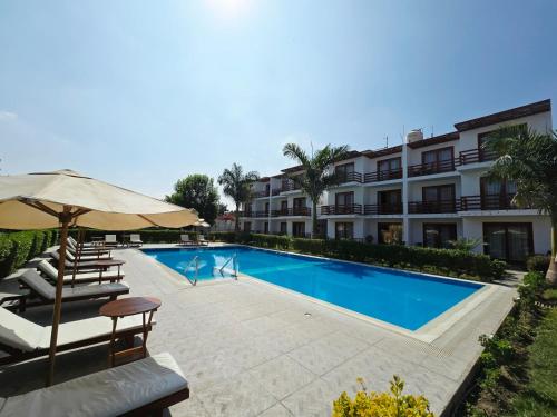 a swimming pool with chairs and an umbrella next to a building at Hotel La Colina in Ica