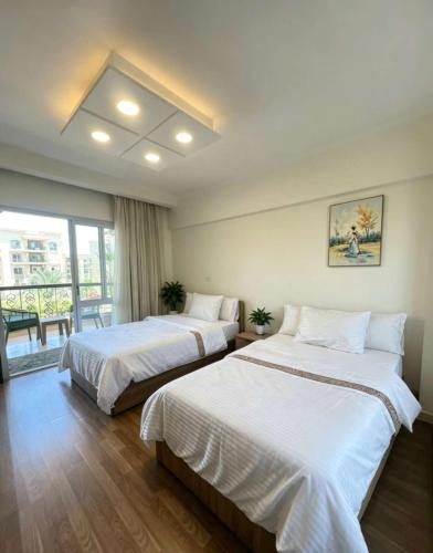 two beds in a room with a balcony at SUNSKY Apartment Hotel in New cairo