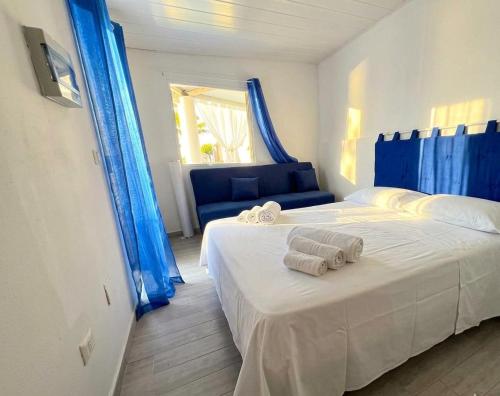 two beds in a bedroom with blue curtains and towels at I Venti di Vulcano in Vulcano