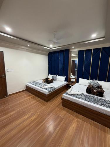 two beds in a room with blue walls and wooden floors at Hotel Royal Suites in Ajmer