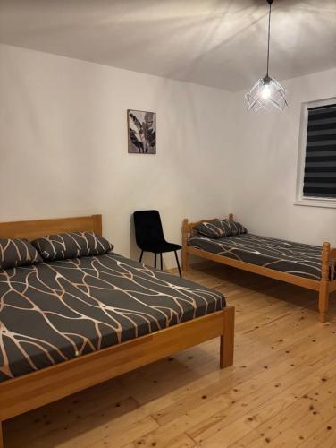 a bedroom with two beds and a chair in it at Vikendica Dajana in Banja Luka
