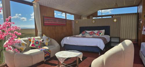a bedroom with a bed and two chairs and a table at Titicaca Wara wara Lodge in Puno