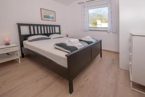 a bedroom with a large bed with white sheets and a window at Holiday house Casa Vida in Rakalj