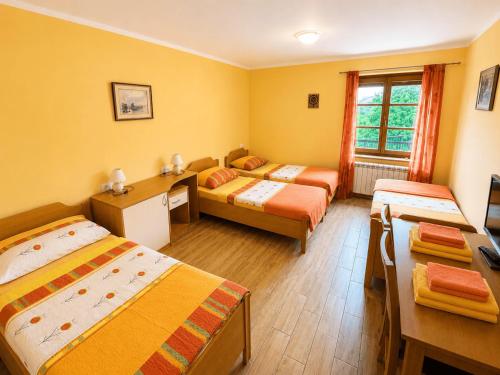 a room with three beds and a desk in it at Domačija Harmonija in Vremski Britof