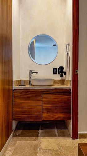 a bathroom with a sink with a round mirror at Amaka Calma Tulum by Cercana in Tulum