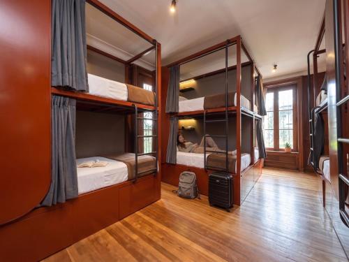 a room with three bunk beds and a person in it at Sereno Hostels in Bogotá