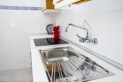 um lavatório de aço inoxidável numa cozinha branca em Apartamento ToleTum em Toledo