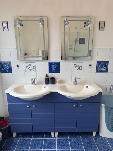 a blue bathroom with two sinks and a mirror at Le Paradis in Belfort