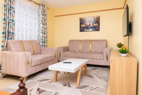 a living room with two couches and a tv at Almarg homes in Nakuru