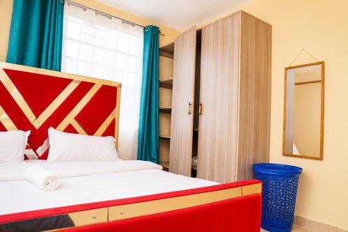 a bedroom with a bed with a red headboard and a mirror at Almarg homes in Nakuru