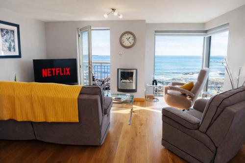 a living room with a couch and chairs and a clock at Portstewart promenade apartment with sea views in Portstewart