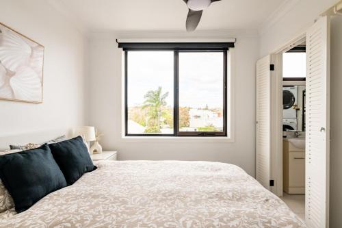 a white bedroom with a bed and a window at Richmond apartment close to MCG in Melbourne