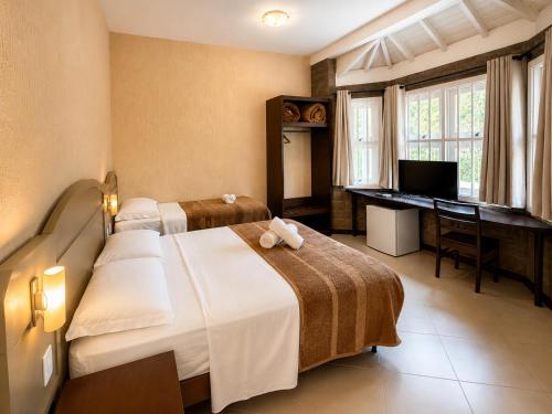 a bedroom with two beds and a desk and a piano at Pousada Nosso Lar in Gramado