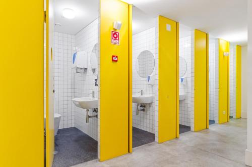 a row of yellow stalls in a bathroom with sinks at Salt&Flow in Parede