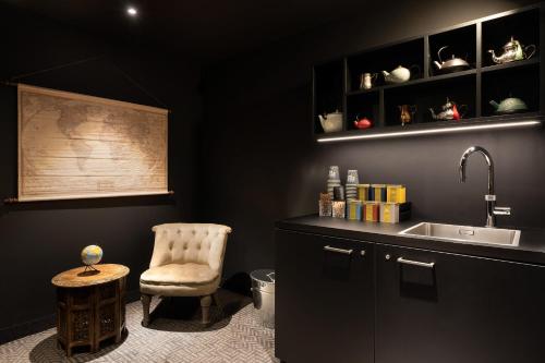 Eine schwarze Küche mit einem Stuhl und einem Waschbecken in der Unterkunft Ruby Claire Hotel Geneva by IHG in Genf