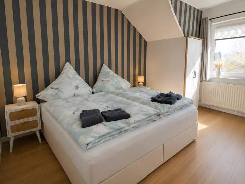 a bedroom with a large white bed with black pillows at Gaestehaus Nuke in Langeneß