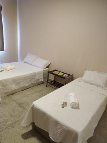 a room with two beds and a table at Loft Campinho 3 in Estação Inhoaíba