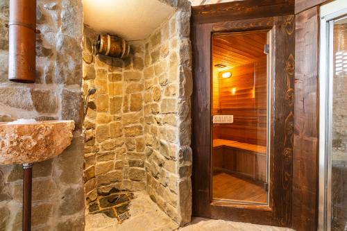a bathroom with a walk in shower next to a stone wall at Agriturismo Scannano in Serre di Rapolano