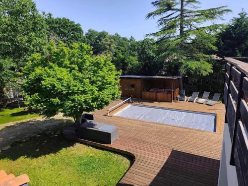 a backyard with a swimming pool on a wooden deck at Le Chêne Vert - Grande Villa familiale avec piscine - Bassin d'Arcachon in Arès