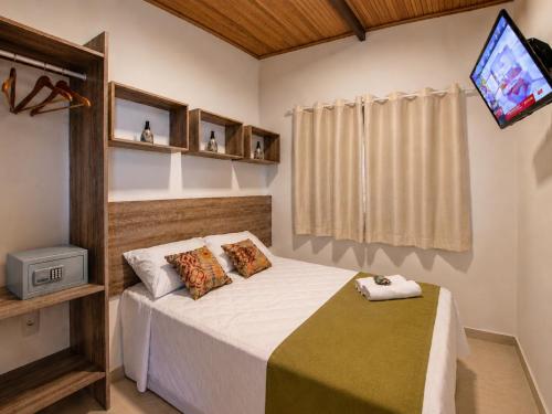 a bedroom with a bed with a tv on the wall at Flats Morro de São Paulo in Morro de São Paulo
