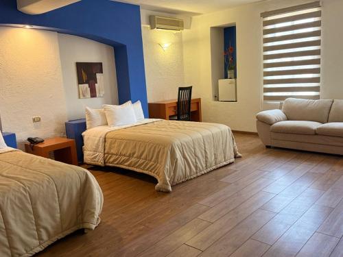 a hotel room with two beds and a couch at Hotel Tlayolan in Ciudad Guzmán