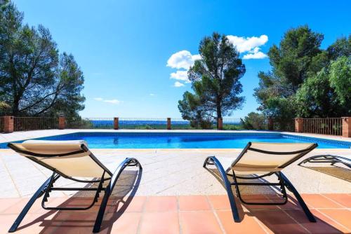 two chairs sitting next to a swimming pool at Masia Garriga in Tarragona