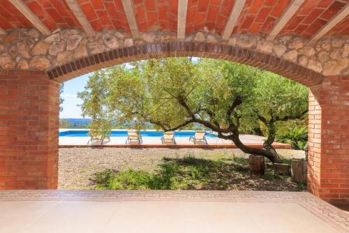 an archway in a brick building with a tree at Masia Garriga in Tarragona