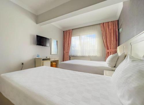 ein Hotelzimmer mit zwei Betten und einem Fenster in der Unterkunft ROYAL 52 in Altınordu