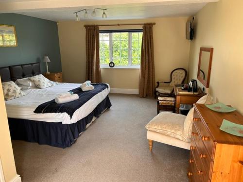 a bedroom with a bed and a chair and a window at Ganton Greyhound Hotel in Ganton
