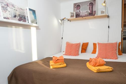 リスボンにあるBombarda Studioのオレンジのタオルが付いたベッドが備わる客室です。