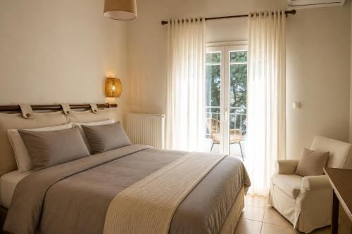 a bedroom with a bed and a chair and a window at Niobe Luxury Residence in Loutraki