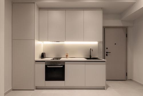 a kitchen with white cabinets and a sink at Sola District Volos in Volos