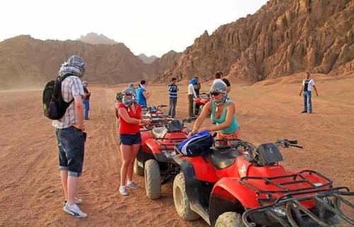 a group of people standing around atvs in the desert at Luxor Star ATV in Luxor