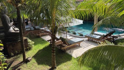 a pool with lounge chairs and a palm tree at ABG Villas - Agrowisata Amed in Amed