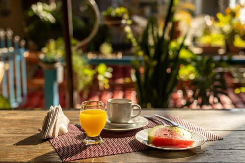 a table with a plate of fruit and a cup of orange juice at Studio Bangalô Belém Hospedagem in Belém