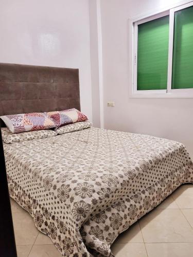 a bedroom with a bed with a comforter and a window at عين السلطان ain sultan in Imouzzer du Kandar