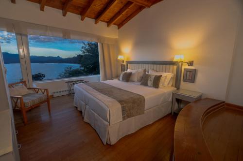 a bedroom with a large bed and a large window at Sol Arrayan Hotel & Spa in Villa La Angostura