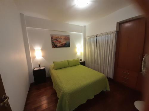 a small bedroom with a green bed with two lights at Reflejo de Mar in Villa Gesell