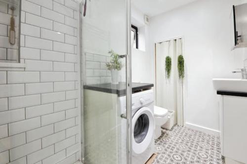 a bathroom with a washing machine and a toilet at King size room in home for couple or females in Hornchurch