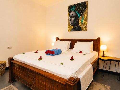 a bedroom with a bed with a portrait of a woman at Tamu House Paje in Paje