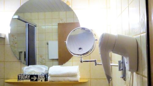 a bathroom with a mirror and towels on a shelf at Hotel Garni Silberburg - Schwarzwald-Plus Karte in Bad Wildbad