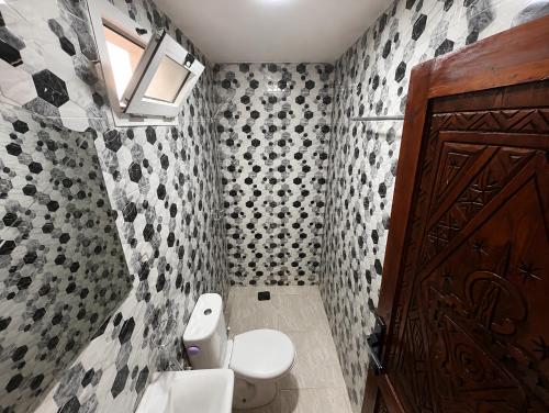 a bathroom with a toilet and a brown door at Happy Waves Morocco - Surf Hostel Tamraght in Tamraght Ou Fella
