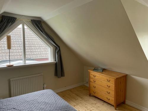 a attic room with a bed and a dresser and a window at Gästhus Vejbystrand in Vejbystrand